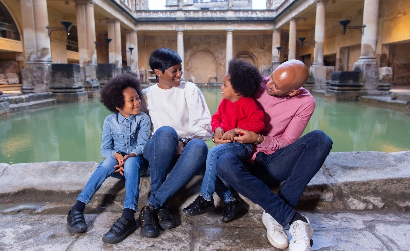 A family sat on the edge of The Great Bath